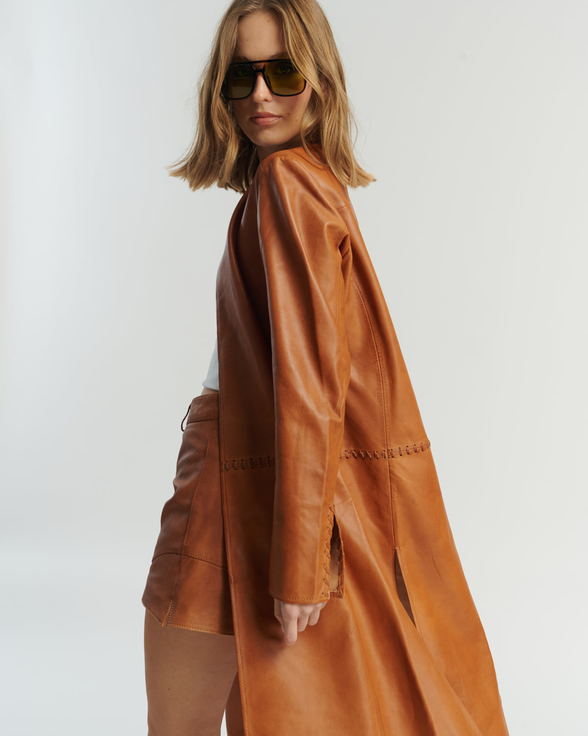 Espalda capa larga cuero camel HER Chile — detalle trenzado y textura cuero ovino 100%