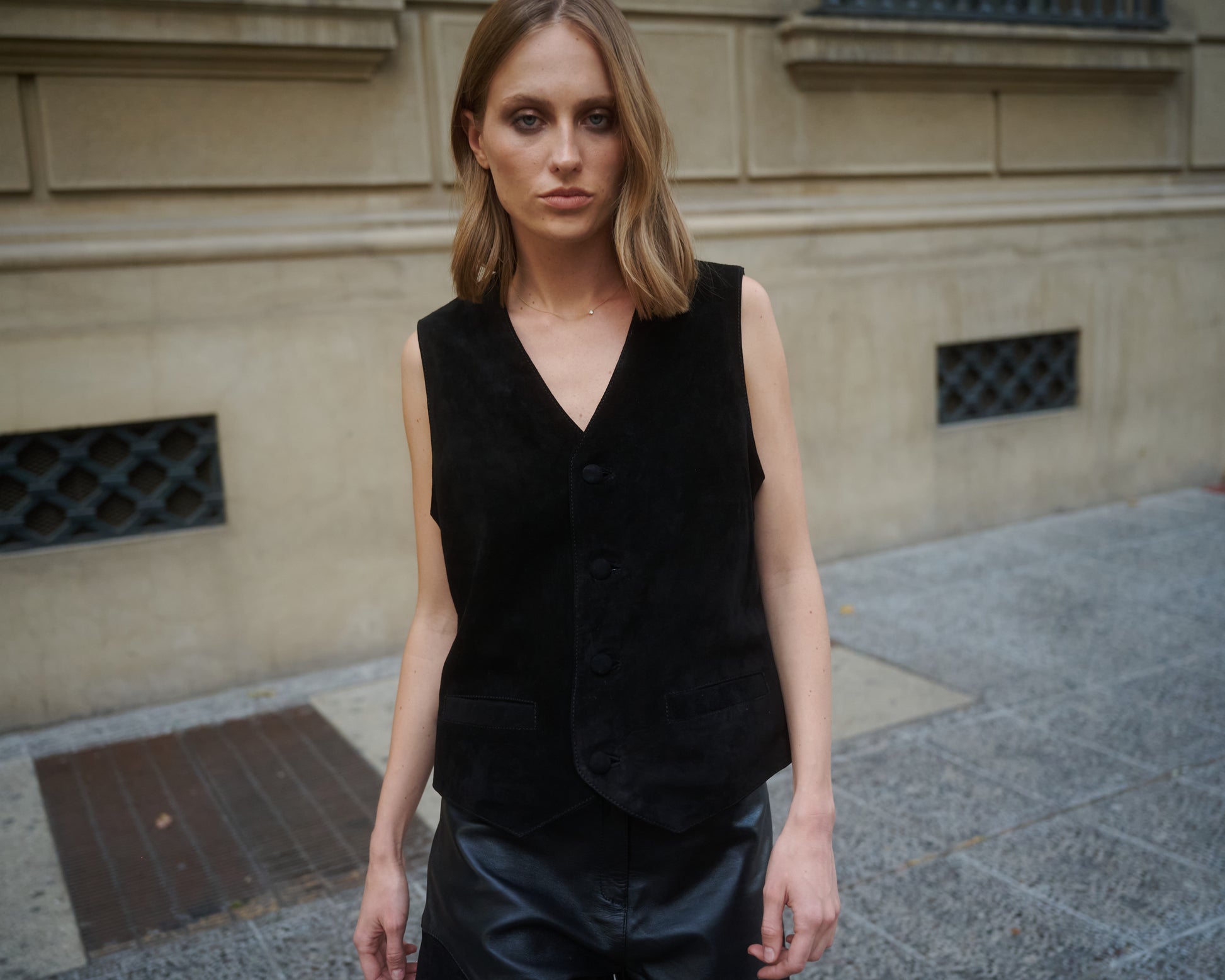 Outfit mujer con vest negro gamuza sobre shorts de cuero 