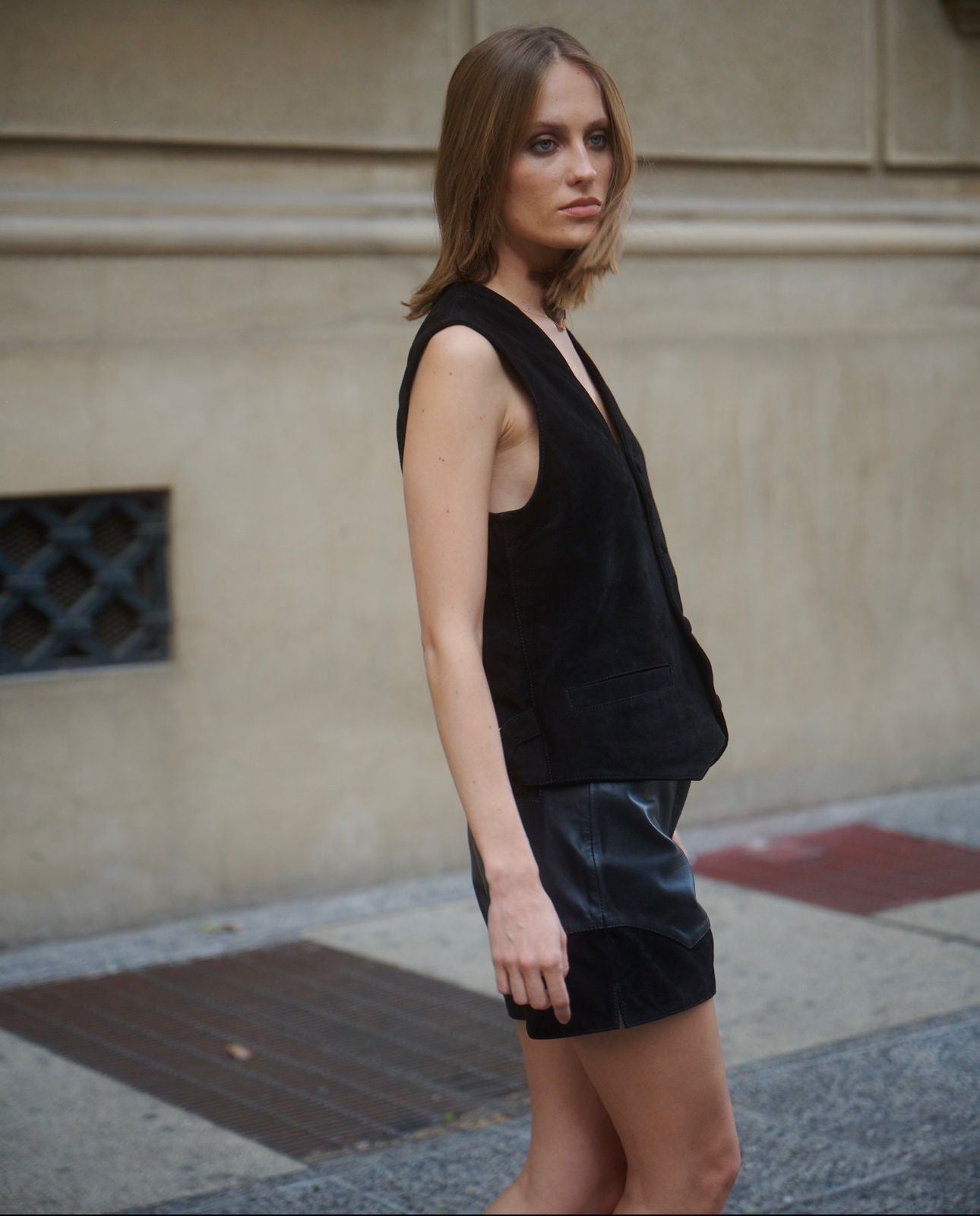 Outfit mujer con vest negro gamuza , vista lateral con detalles, sobre shorts de cuero y botas